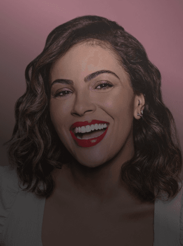 Mulher parda com batom vermelho, cabelo ondulado e sorrindo